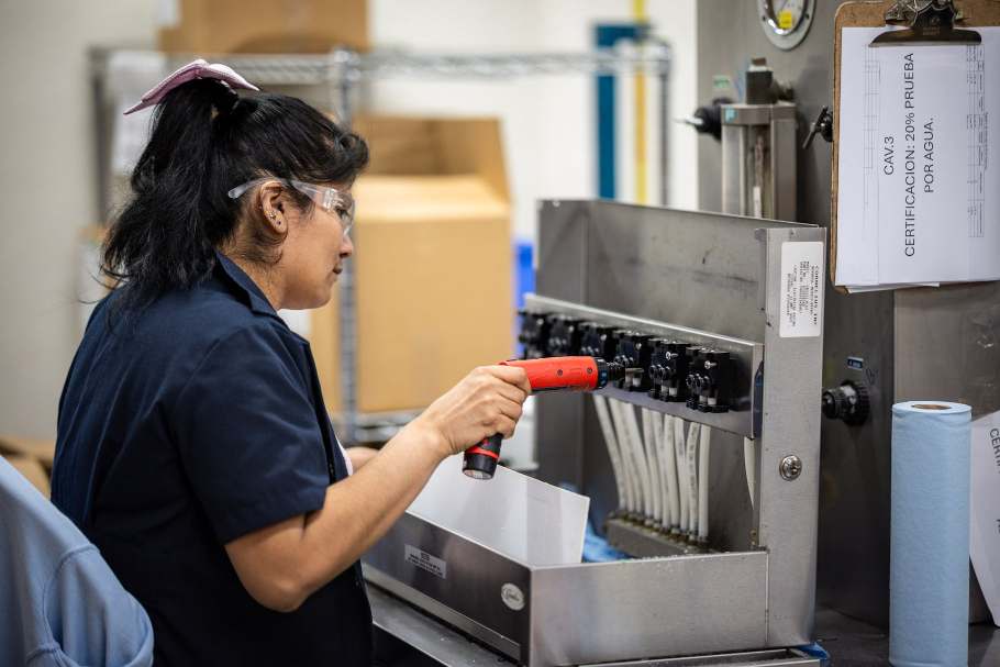 Marmon Renew technician using a powered driver on a manifold next to a clipboard tracking certification testing