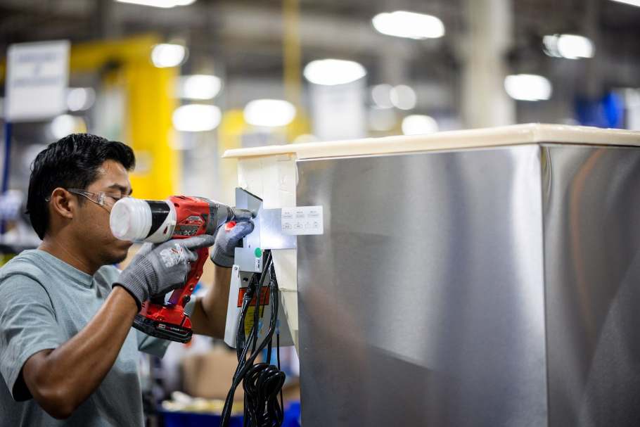 Marmon Renew technician fastening a stainless beverage cabinet on the remanufacturing floor